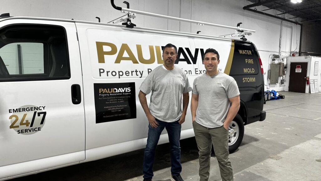 Paul Davis Restoration of Middlesex County emergency response team standing beside branded restoration service van in New Brunswick NJ offering 24/7 water, fire, mold, and storm damage restoration services